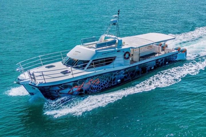 Speedboat with graffiti design gliding on blue water, viewed from above.